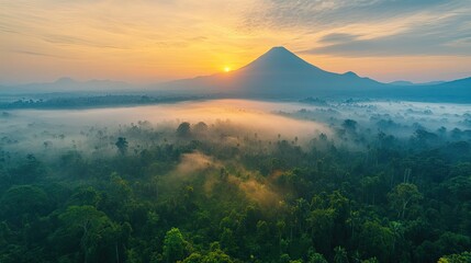 Aerial view of majestic mountains shrouded in fog and forests, illuminated by sunrise and dramatic skies 