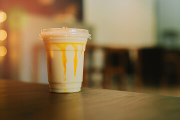 Refreshing Gelato Beverage in a Plastic Cup with Dripping Caramel Sauce in a Cozy Café Setting