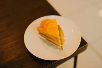 Delicious orange cake slice served on a white plate, showcasing vibrant colors and appetizing textures in a cozy cafe setting