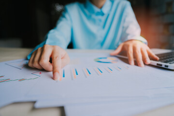 Business Professional Analyzing Charts and Graphs While Working on a Laptop at a Modern Desk