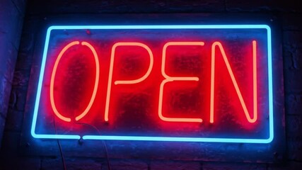 Neon open sign glowing in blue and red colors on dark background  