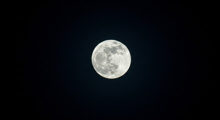 Fototapeta premium Full moon glowing brightly in the inky black night sky.