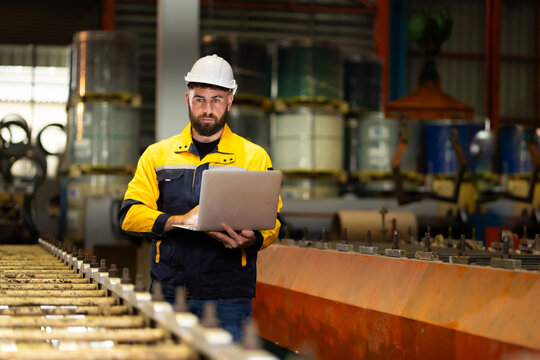 Laptop computer : blue collar working production line : Caucasian man engineer worker working control sheet metal roof tile roll forming machine at metal sheet profiling factory. Industrial production