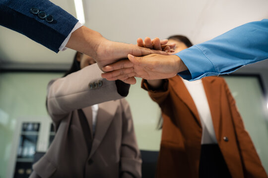 business people holding each others wrists, join hands together, support and unity, team strength and power, colleagues involved in team building activity. - Powered by Adobe
