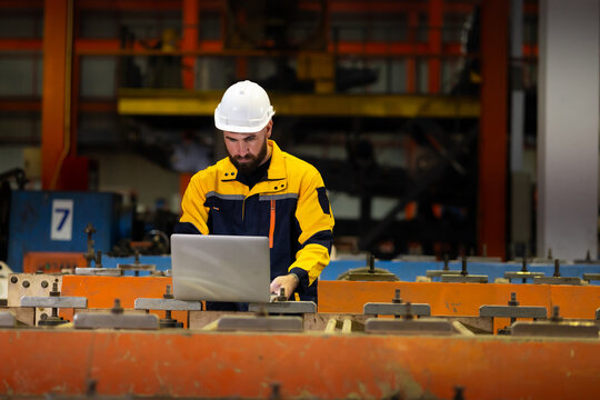 Laptop computer : blue collar working production line : Caucasian man engineer worker working control sheet metal roof tile roll forming machine at metal sheet profiling factory. Industrial production