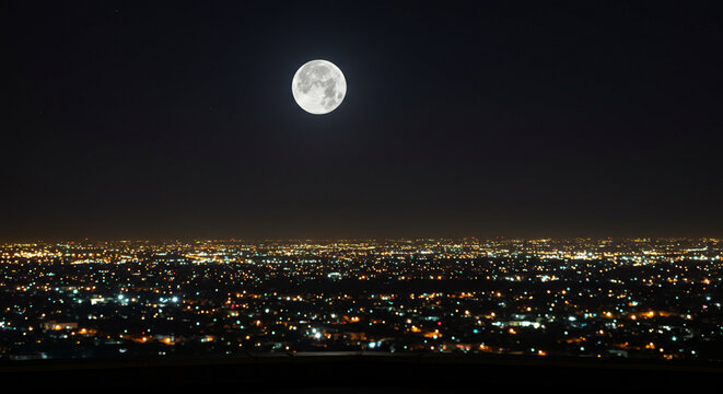 Full moon over a city at night, illuminated by city lights. - Powered by Adobe