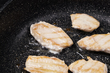 Grilled chicken fillets sizzling in a non-stick frying pan, showcasing golden-brown sear marks,...