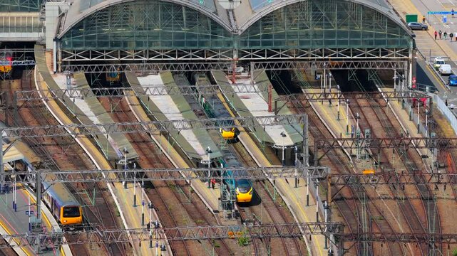 Aerial video of a busy Manchester Train Station platforms zoomed from a distance 