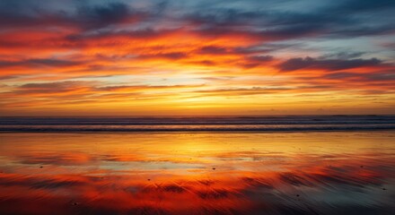 Fiery sunset sky reflects on wet beach sand with gentle ocean waves