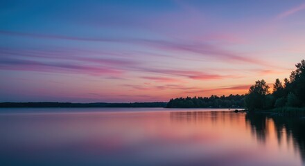 Serene lake at dusk with vibrant pink and blue clouds reflecting on the calm water