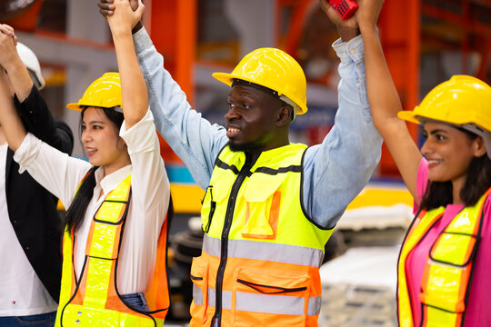 Celebrate Raise hand up. Unity and teamwork. Ethnic diversity engineering team standing together. Group of professional engineering people wearing hardhat safety helmet meeting Celebrate good news