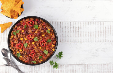 Bowl of meat mexican spicy stew with beans and corn chili con carne on white wooden background. Top view. Copy space.