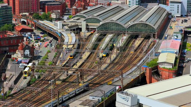 Aerial video of a busy Manchester Train Station platforms zoomed from a distance 