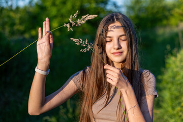 Peaceful girl with grass shadows on face. A serene teenage girl stands with eyes closed as wild...
