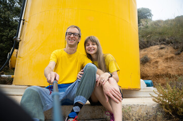 Happy Couple Taking a Selfie in a Rural Outdoor Setting with Cheerful Yellow Background