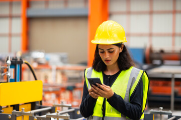 Cell phone smartphone : blue collar working production line : Indian female engineer worker working sheet metal roof tile roll forming machine at metal sheet profiling factory. Industrial production