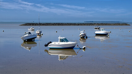 Boats of Chatelaillon-plage in low tide and reflections on the surface of the remaining water. Châtelaillon-Plage is a commune in the Charente-Maritime department