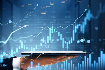 Businessman hand holding tablet with digital financial stock market data, candlestick chart and upward graph overlay on abstract blue background.