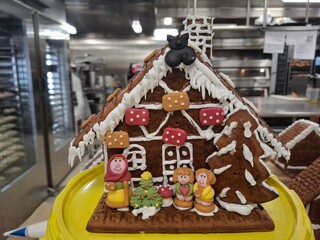 Decorative Gingerbread House with Figures and Holiday Ornaments in Bakery
