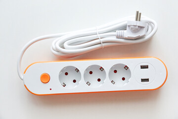 White power strip with orange details, three sockets, and two USB ports for charging devices. Compact and practical extension cord for household or workplace electronics connection