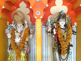 Lord Ganesha and Lord Shiva statues decorated with flower garlands in hindu temple in Rishikesh, India.