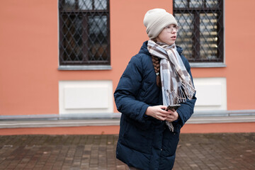 Teenager Girl Walking Alone on City Street with Smartphone. Portrait of 14 years old girl wearing...