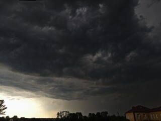 Dramatic landscape with dark storm clouds looming over the horizon, contrasted by a bright glow...