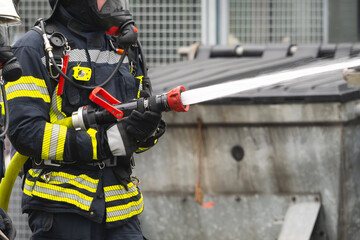 Naklejka premium Firefighting with breathing apparatus in action – targeted water deployment for fire suppression