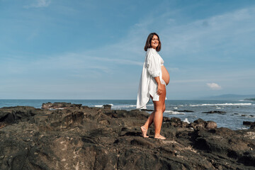 Side view of pregnant woman with eyes closed, hand on belly, embracing connection and inner...