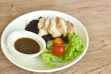 grilled slice chicken black pepper on riceberry with tomato and lettuce on plate dipping Thai spicy...