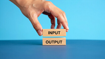 A hand hovers over wooden blocks labeled input and output, symbolizing data processing and information flow