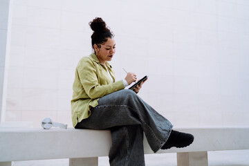 Woman engaged in digital work, sketching or writing on tablet with a stylus. Her concentrated...