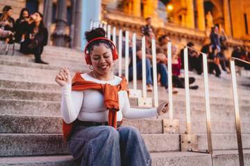 young woman enjoys music through wireless headphones, immersed in playlist or podcast, relaxing in...