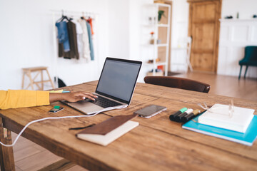 Close-up of young woman browsing on laptop at cozy home office desk, surrounded by everyday digital tools and supplies for effective remote work and creative planning