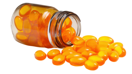 Vibrant orange vitamin capsules spilling from a glass jar on a white isolated background.