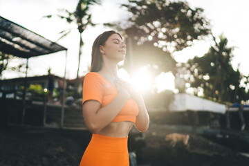 Brunette woman in orange sports gear engages in beach circuit training, illustrating commitment to...