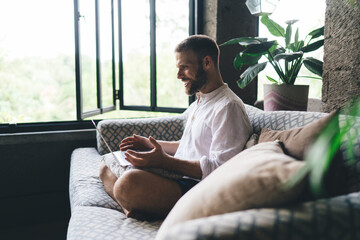 Freelancer gesturing enthusiastically during video call from sofa. Visualizes digital...