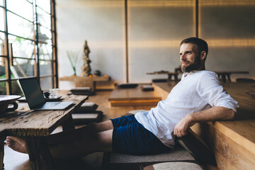Remote worker in minimalist space pausing after laptop session, capturing balance between...