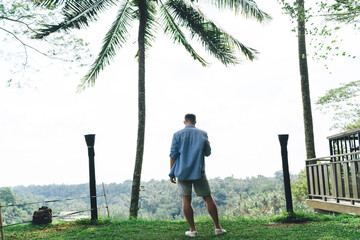 Solo freelancer standing with smartphone, looking at jungle horizon, expressing mobile autonomy,...