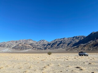 Expedition in the vast desert landscape surrounding mountain ranges under a clear blue sky