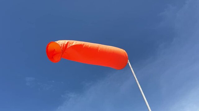 Windsock indicator of wind on runway airport. Wind cone indicating wind direction and force. Horizontally flying windsock (wind vane), offshore oil and gas