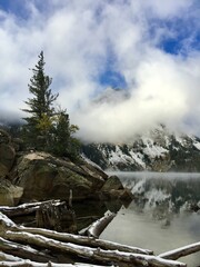 Snowy landscape with fog over lake and mountains during autumn afternoon in national park