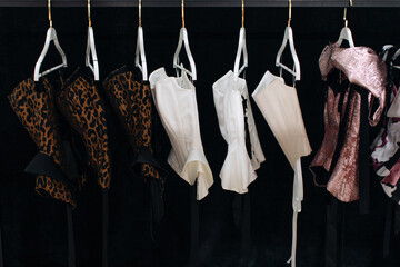 Stylish Women's Elegant Corsets with Laces hanging in a row on black background