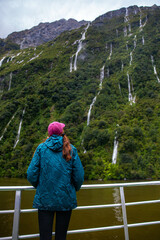 adventurous girl admires numerous waterfalls cascading down a mountain cliff during heavy rainfall,...