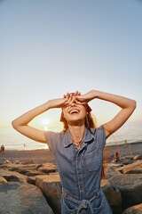 lifestyle woman enjoying sunset in modern boho-western denim dress at beach with film color warm...