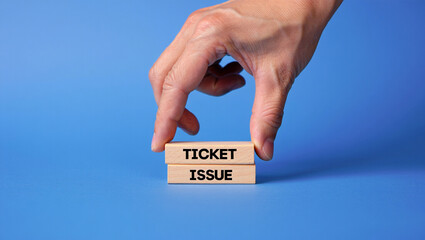 A hand places a wooden block with the word ticket on top of a block with the word issue