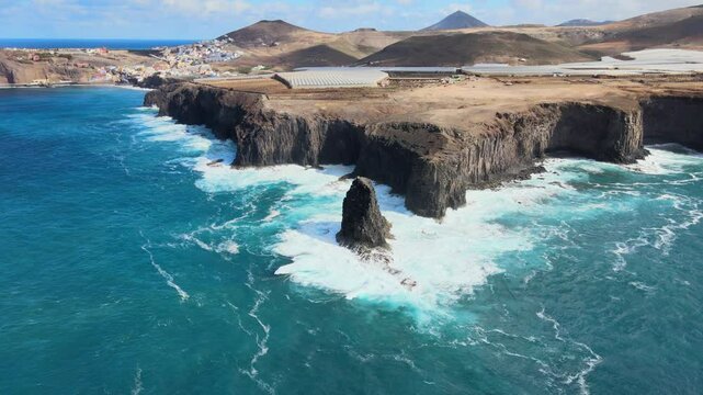 Turquoise water waves crashing on the rocky cliff of Risco Partido in Gran Canaria