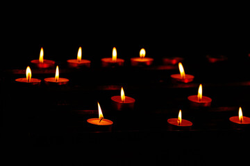 Warm glow of lit tealight candles in the dark
