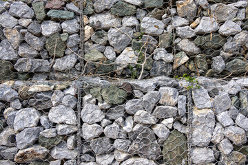 gabion wall, showcasing the texture of the grey stones and the wire mesh. The image highlights the...