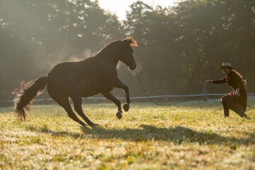 Cowgirl lunging her horse in the field and bonding